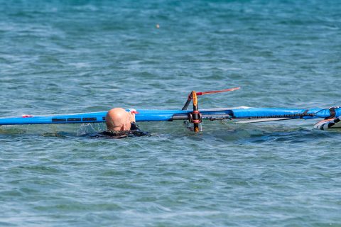 Ensure you have the wind hitting the mast at 90° and after you have swam backwards with the rig, begin to draw it up and across to draw air underneath it. You can do this with one hand once you have released the water off the sail or with both hands.