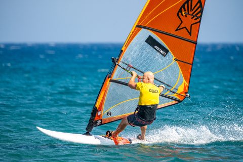 Spot your space, with sufficient wind. Shift your backhand back, and then unhook by staying out and only bending the elbows. Back foot out after this and scissor to get speed, and lighten the sail.