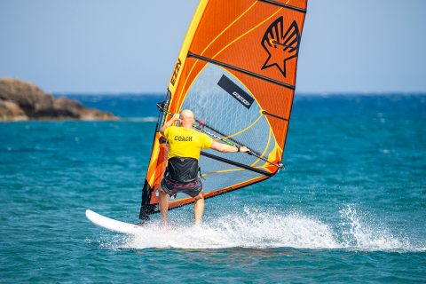 With good speed, and a light sail, you are ready to look and roll forward in order to carve. Ensure your back foot is right on the rail and back. Duck the rig early by tipping the rig forward, towards the nose, with your old backhand.