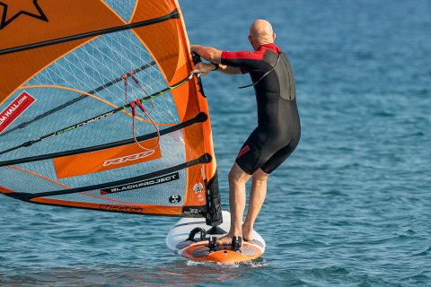 Rotate the rig and keep looking forward. You may touch down here, but if you have speed you can pop back up with some back foot pressure. Pressure on your heels as you do this will help you come back to more across the wind. You do not have to rush to grab the rig with the back hand here. Sometimes I am coming out of my gybe on the foil and only have my front hand on the boom as I send the rig forwards.