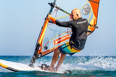 Unhook, by bending elbows and staying outboard. Get feet out of the footstraps, back foot first. Pulling down on your arms really makes this smoother. Place your back foot next to front straps.