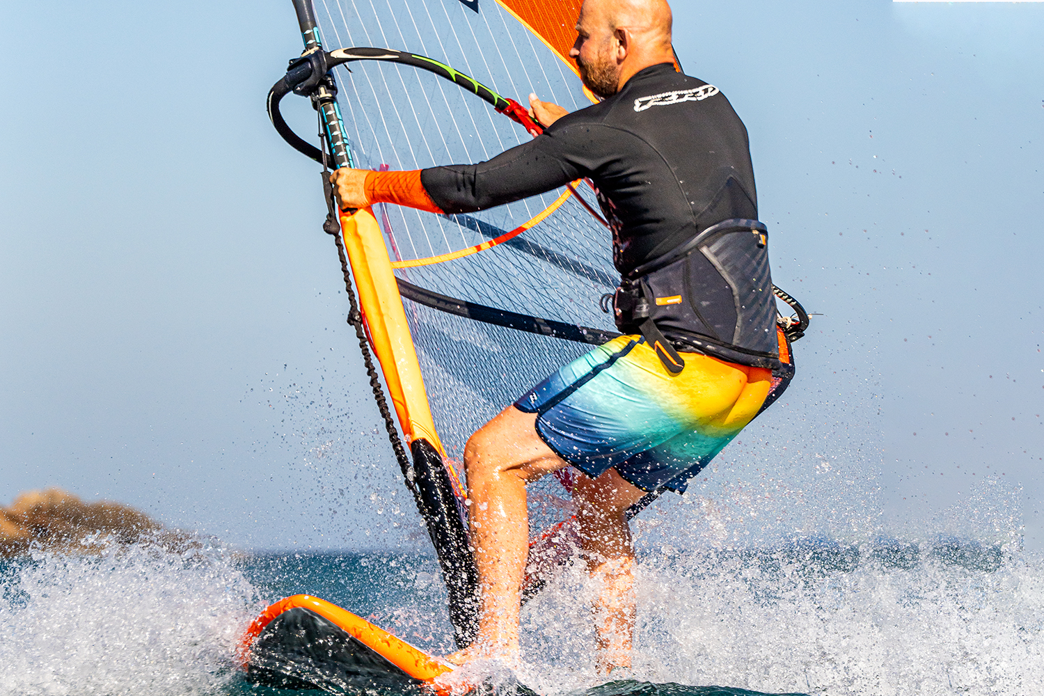 Before head to wind be ready to make the change. Go for an extra hip swing forwards, and out. Wrapping the front foot more around the mast foot helps this. These actions lighten your back foot so it can move. Keep your mast arm straight!
